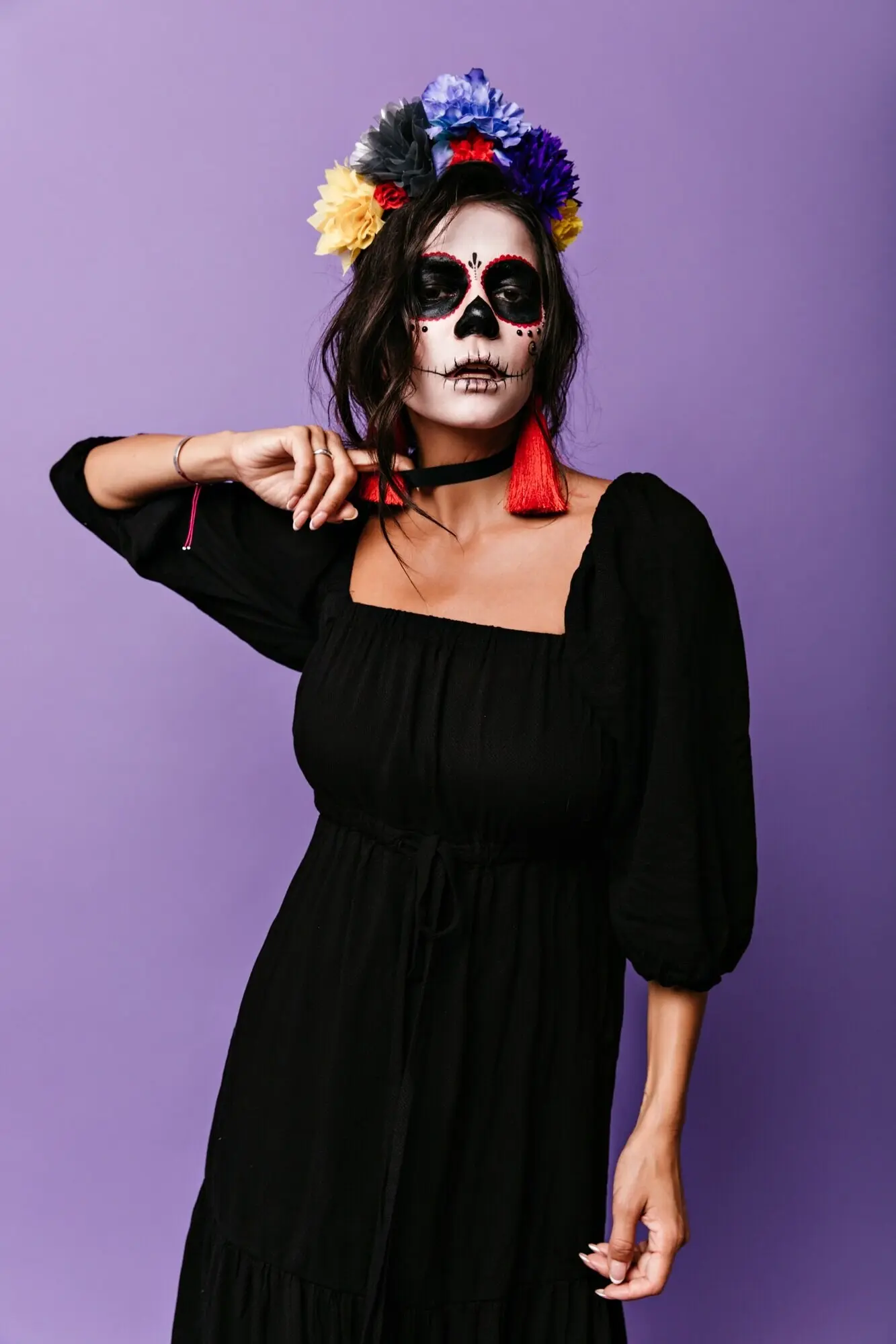 Eine geheimnisvolle Frau mit dem Bild eines Skeletts im Gesicht versucht, sich die schwarze Halskette vom Hals zu reißen.